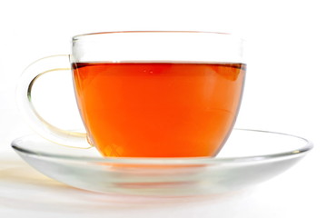 hot black tea in transparent glass cup on saucer on white background