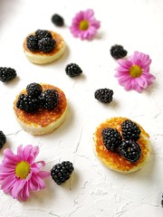 BlackBerry and pancake on aged wooden background with flowers and coffee