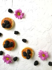 BlackBerry and pancake on aged wooden background with flowers and coffee