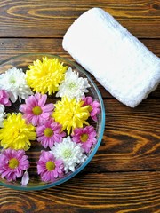 manicure with foot Spa from flowers on wooden background and white towel