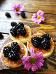 BlackBerry and pancake on aged wooden background with flowers and coffee
