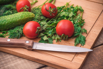 Tomatoes, cucumbers and green stuff on wooden table. Diet vegetarian food concept.