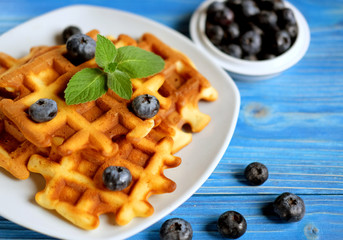 Homemade waffles with blueberries in plate on wooden table