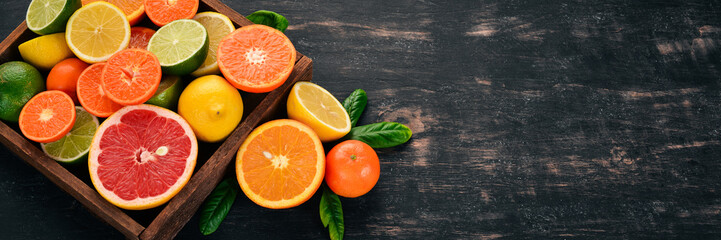 Assorted citrus fruit in a wooden box. Orange, tangerine, grapefruit, lemon. On a wooden background. Top view. Copy space.