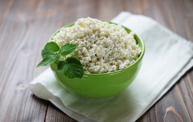Cottage cheese with mint in a green bowl on a white napkin. Top 