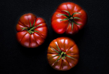 Tomatoes on black stone  background with copy space. Fresh ripe organic tomatoes 