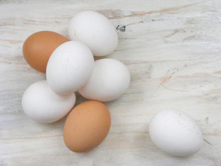 A lots of white and brown chicken eggs on white shabby background flat view