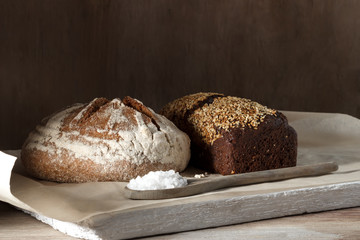 Round and rye black bread with salt on a wooden background