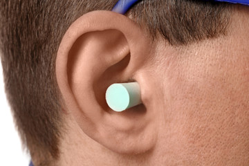 Male worker with ear plug, closeup. Health and safety at workplace concept