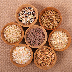 Variety of rice and grains in bowls on linen tablecloth. Square format with top view.