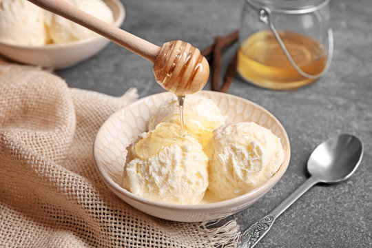 Pouring honey onto delicious vanilla ice cream in bowl