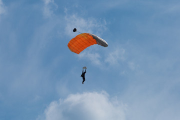 Parachutist with Orange Parachute against Clear Blue Sky