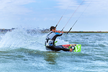 Naklejka premium Man riding a kite surfing on the waves in the summer.