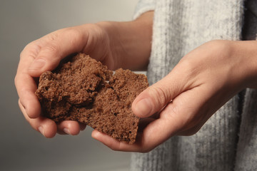 Poor woman holding piece of bread, closeup