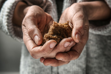 Poor woman holding piece of bread, closeup
