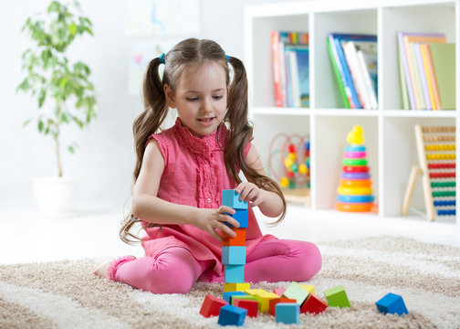 cute child girl playing with block toys in daycare centre