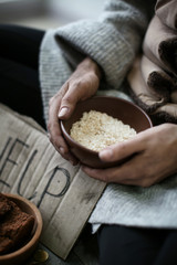 Poor woman holding bowl with rice, closeup