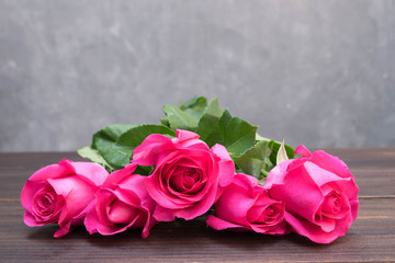 Pink rose on brown wooden background