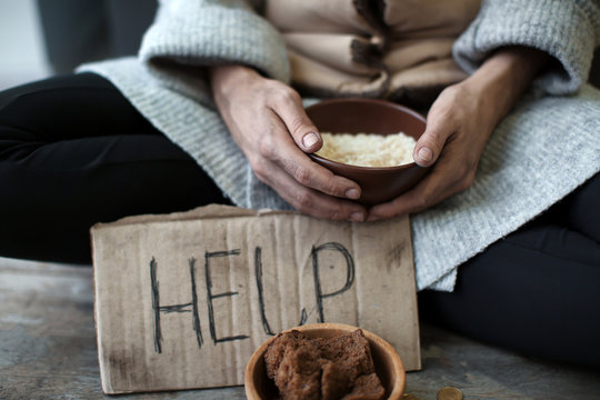 Poor woman holding bowl with rice, closeup