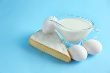Fresh dairy products and eggs on color background