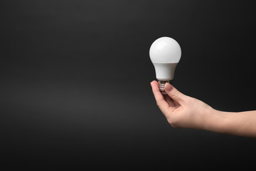 Woman holding LED lamp on dark background