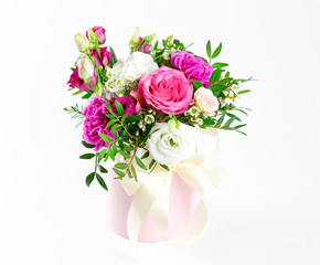 Composition of flowers in a pink hatbox. Tied with wide white ribbon and bow