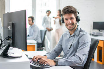 Smiling man customer support phone operator with headset working in call center.