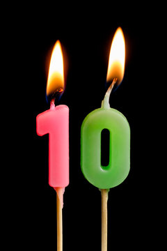 Burning candles in the form of ten figures (numbers, dates) for cake isolated on black background. The concept of celebrating a birthday, anniversary, important date, holiday, table setting