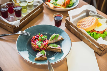 Salad vinaigrette, hamburger with egg, Caesar salad and alcohol drinks on table in cafe.