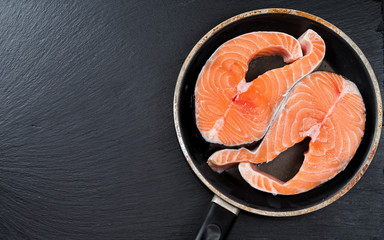 Fresh raw unprepared fish salmon or trout, steaks, in a frying pan, top view
