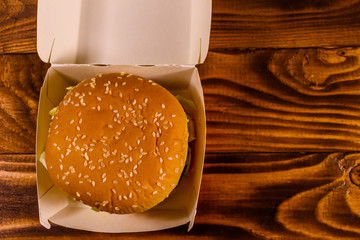 Fresh hamburger in paper box on the rustic wooden table. Top view
