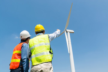 Engineer and Architect discuss over Digital Wireless Tablet and Clipboard while working at Wind Turbine Power Generator.