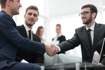 Partners concluding deal and shaking hands in the presence of team members