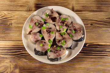 Sliced mackerel with spices on wooden table. Salted scomber on a plate