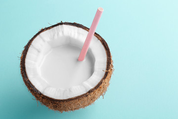 Coconut milk drink in a halfed coconut on a turquoise background. Copy space