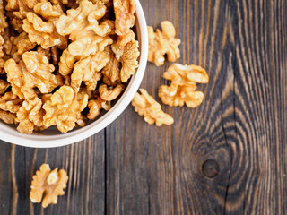 Top view of glass jar with a handful of walnut, circassian nuts on a wooden dark background, selective focus.