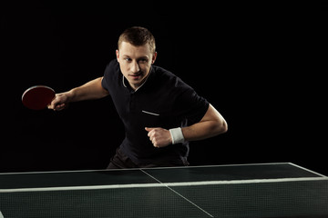 portrait of young tennis player playing table tennis isolated on black
