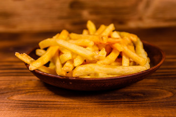 Ceramic plate with french fries on wooden table