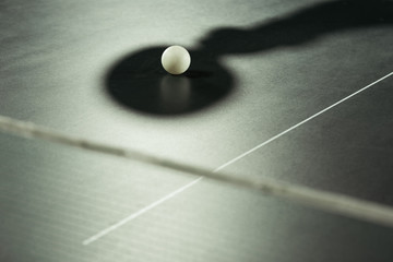 close up view of white tennis ball and shadow on tennis table