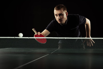 selective focus of focused tennis player in uniform playing table tennis isolated on black