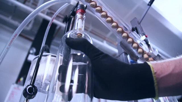 Alcohol bottle being filled by hose at distillery during bottling process