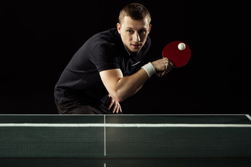 focused tennis player playing table tennis isolated on black - obrazy, fototapety, plakaty