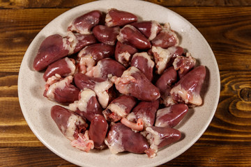 Raw chicken hearts on wooden table