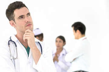 Young teen handsome doctor thinking with hand on chin on white background