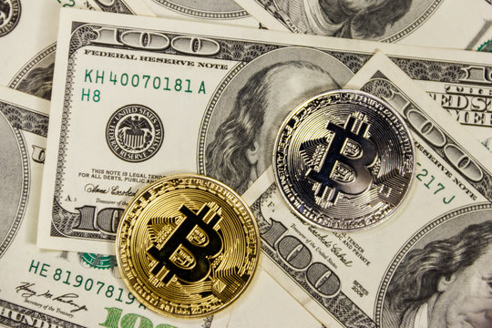 Golden and silver bitcoins on hundred dollar bills background