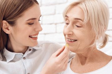 Obraz na płótnie Canvas Girl is caring for elderly woman at home. Girl brings breakfast on tray. Girl is feeding woman.