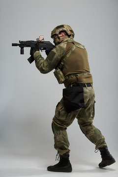 Full-length picture of aiming military man with gun