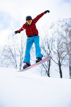 Image of athlete with snowboard jumping in snowy resort