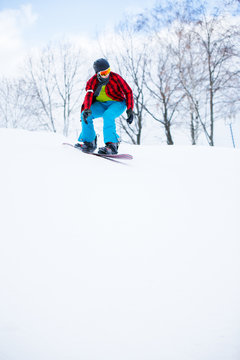 Picture of athlete in checked shirt with snowboard riding in snowy resort