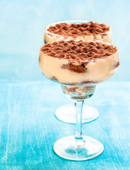 Italian dessert tiramisu in a glass on a blue background.